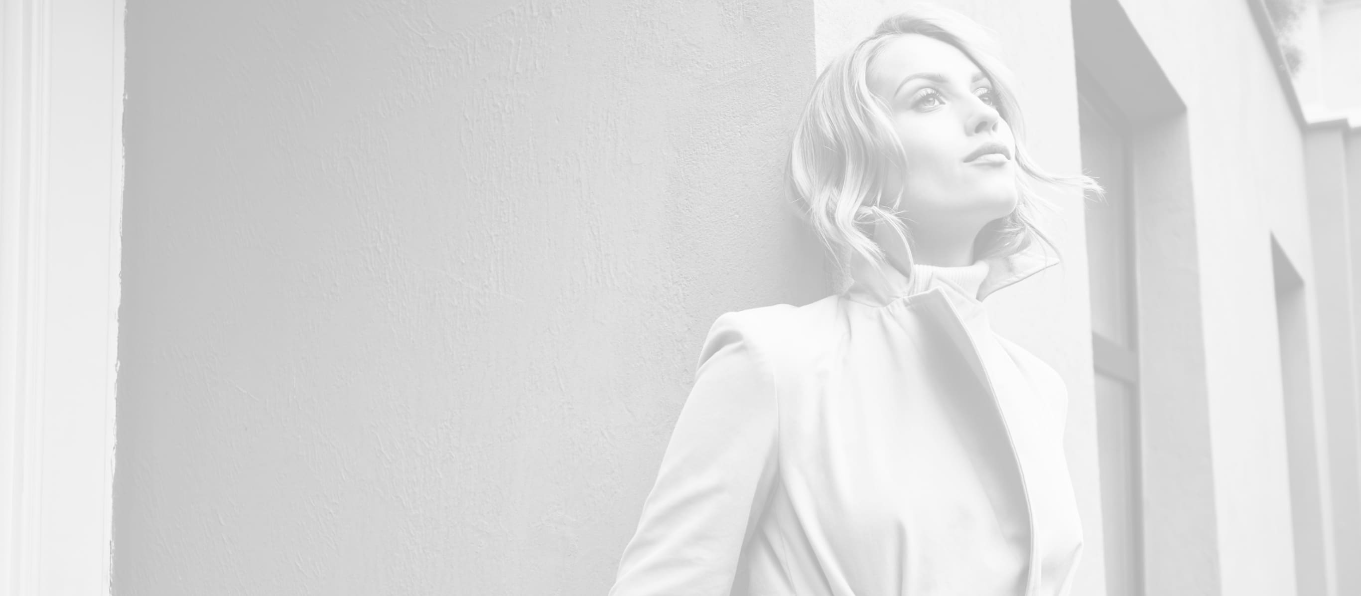 Fashionable woman wearing a jacket, leaning against a wall