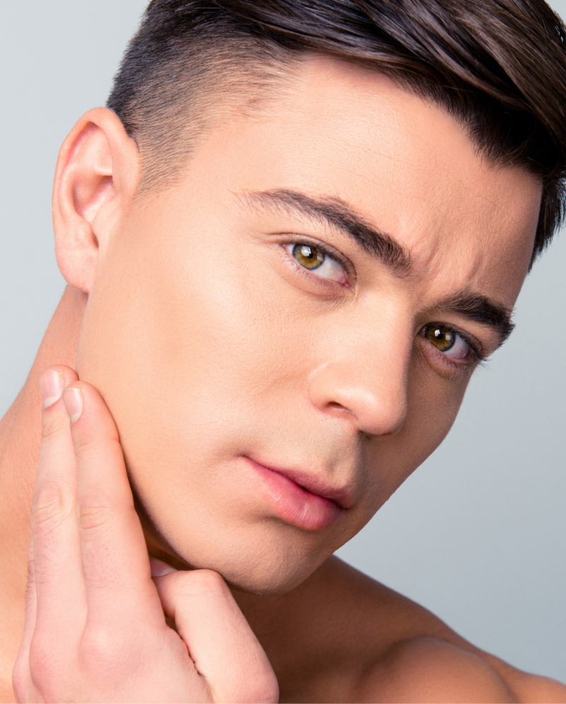 Man with acne scarring touching his face