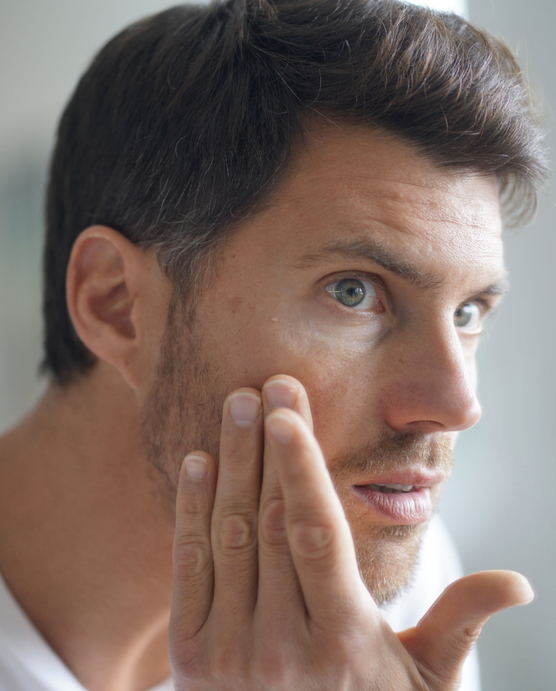 Man with age spots on his face checking out his skin in the mirror