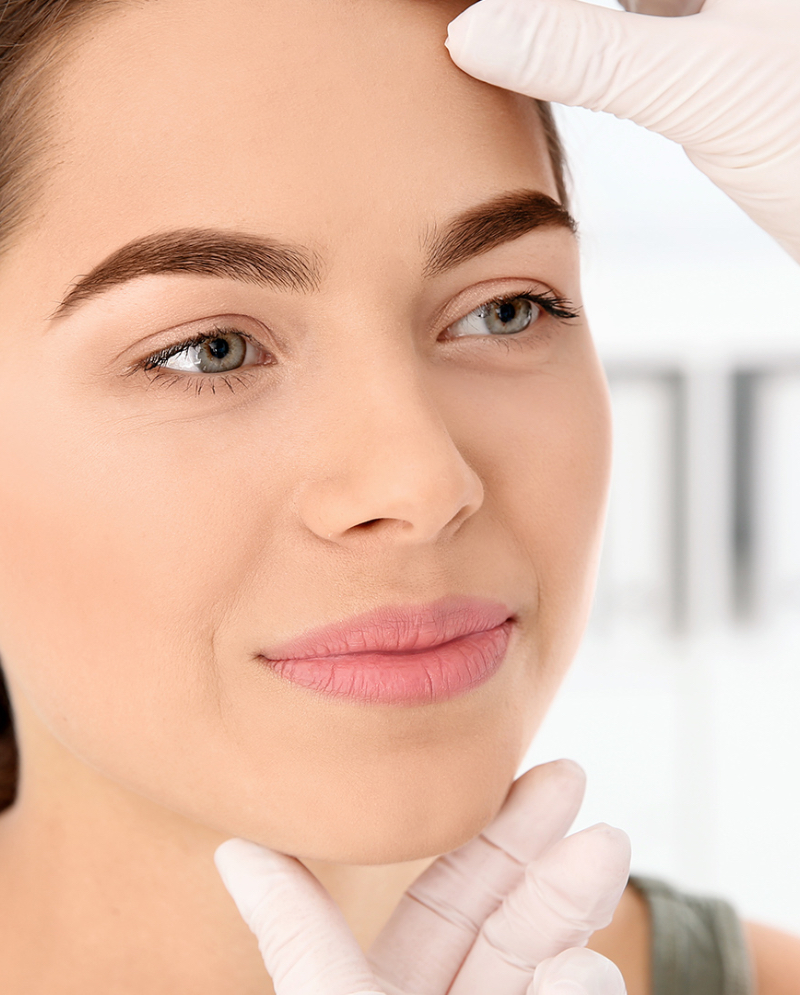 Dermatologist looking at female patient's face
