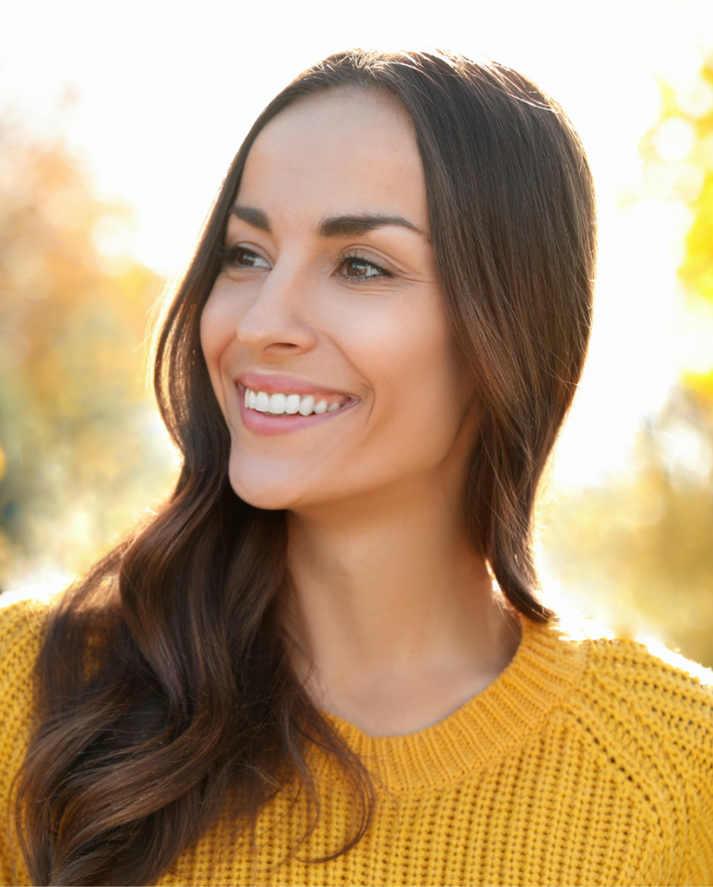 Smiling woman wearing a yellow sweater outdoors