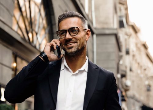 Man wearing a suit walking through a city on his cell phone