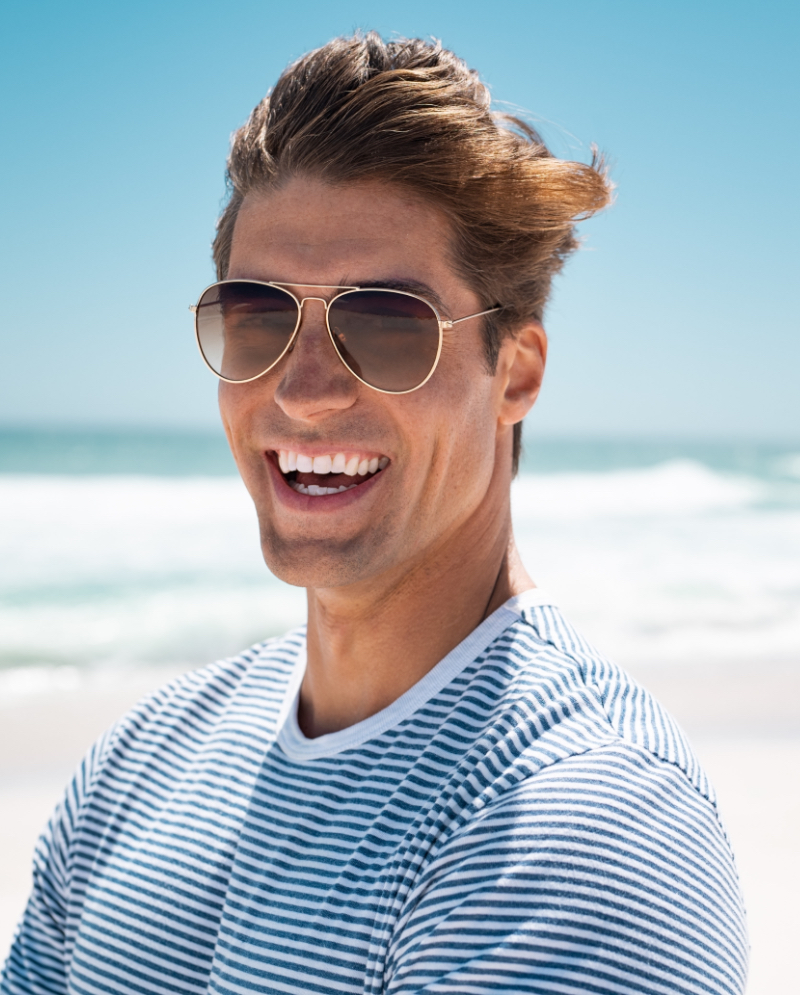 Man wearing sunglasses smiling at the beach
